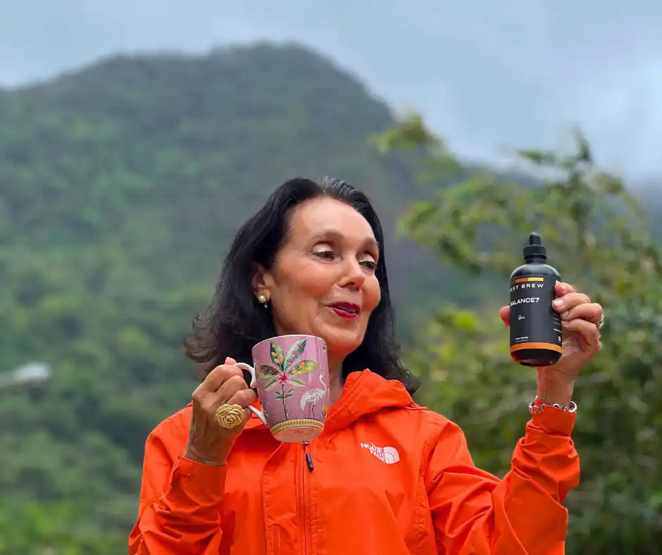 Woman holding mug and black bottle.